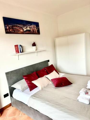 a bedroom with a bed with red and white pillows at Appartamento Roma Est in Lunghezza