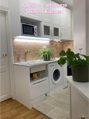 une cuisine avec un lave-linge et un micro-ondes dans l'établissement Chambre privée, sdb partagé, Arc de Triomphe, métro 1, T3b, RER c e a, à Paris