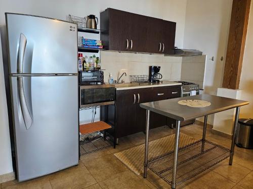 a kitchen with a stainless steel refrigerator and a table at El Remanso Saboga Suites & Studios in Saboga