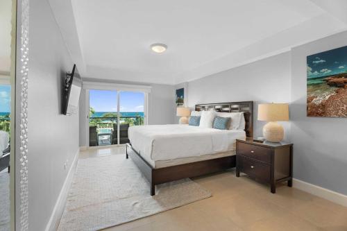 Una habitación blanca con una cama y una ventana en Beachfront - Amazing View 2BR condo - A342, en Palm-Eagle Beach