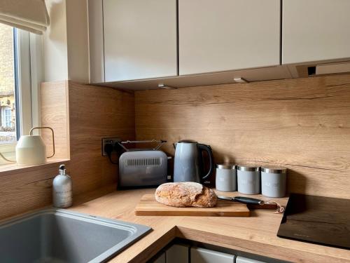 a kitchen counter with a bread on a cutting board at Leaze Garden Cottage - Frome in Frome