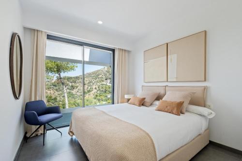 a bedroom with a large bed and a blue chair at Villas Pinares de San Anton - Sea, City, Mountain, Views in Málaga