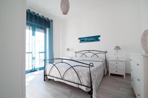 a white bedroom with a bed and a window at Villetta Myalea in Capilungo