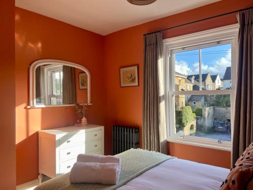 a bedroom with an orange wall and a window at Stylish Victorian Home - Central Frome in Frome
