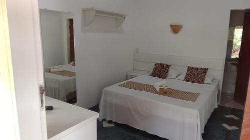 a white bedroom with a dog laying on a bed at Atobá Villas in Paraty