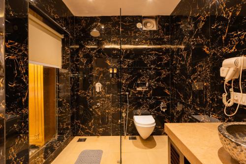 a black bathroom with a toilet and a shower at Emperor Ozran by Alaya Stays in Vagator