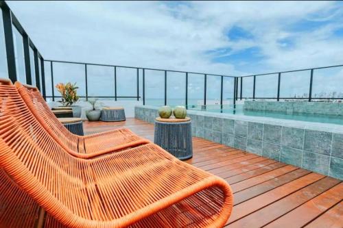 an orange bench sitting on a deck next to a swimming pool at Flat a 50m Praia Caribessa - Get One in João Pessoa