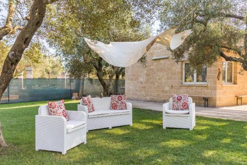 a group of white chairs sitting in the grass at Villa Safiria in Carpignano Salentino