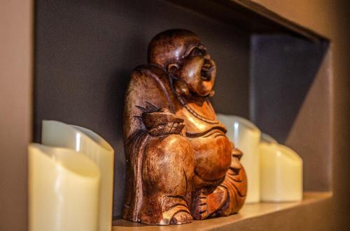 a small wooden statue sitting on a shelf with candles at Le Terre di Maluk in Monte San Vito