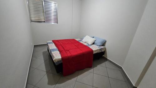 a small bed in a white room with a red blanket at Apê Aconchegante prox Alphaville in Osasco