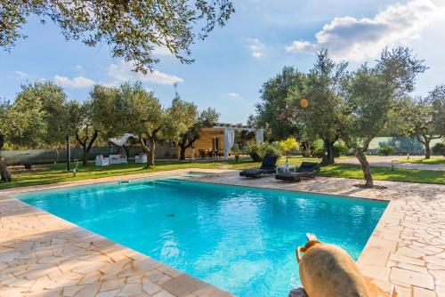 a dog is sitting next to a swimming pool at Villa Safiria in Carpignano Salentino