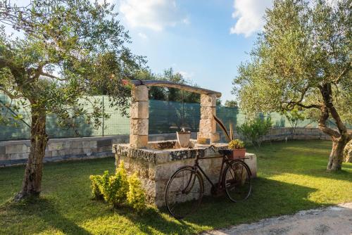 a bike parked next to a stone fountain in a yard at Villa Safiria in Carpignano Salentino