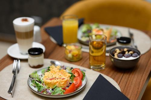 a wooden table with plates of food and drinks at Hotel Bristol Budapest in Budapest