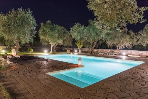 a swimming pool at night with trees and lights at Villa Safiria in Carpignano Salentino
