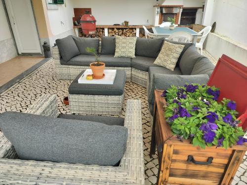a patio with a couch and a table and flowers at Xixi Cama Bed & Breakfast in Bombardeira