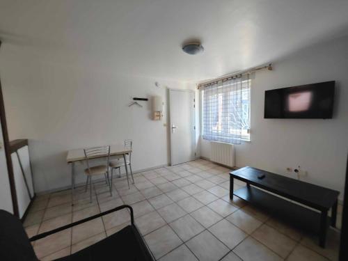- un salon avec une table et une télévision dans l'établissement Chez Lili et Roger, à Schiltigheim