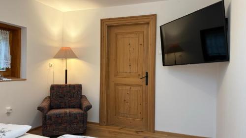 a room with a door and a chair and a television at Almhaus Sparwald in Teuchl
