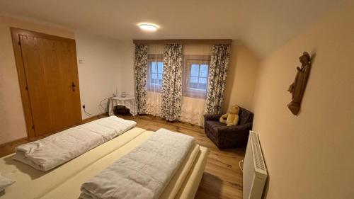 a bedroom with two beds and a chair and a window at Almhaus Sparwald in Teuchl