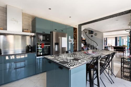 une cuisine avec des armoires bleues et un comptoir dans l'établissement Gites Spa Strasbourg - Villa Ours - SPA Privé, Sauna, Borne d'arcade, Babyfoot, à Ittenheim