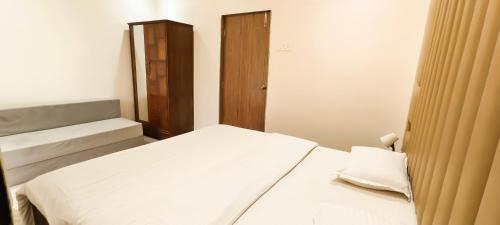 a small bedroom with a bed and a cabinet at Belle-Vue Holiday Homes - 1BHK Apartments in Panchgani