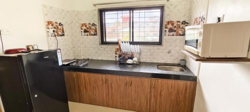a kitchen with a black refrigerator and a sink at Belle-Vue Holiday Homes - 1BHK Apartments in Panchgani