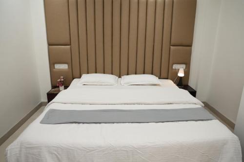 a bedroom with a large white bed with a wooden headboard at Belle-Vue Holiday Homes - 1BHK Apartments in Panchgani