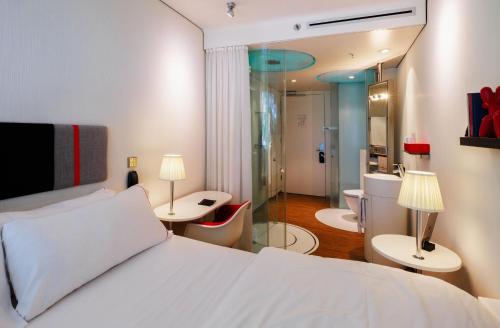 a bedroom with a white bed and two tables and chairs at citizenM Schiphol Airport in Schiphol