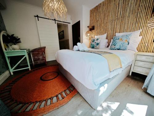 a bedroom with a large white bed and a rug at Beachwood Camps Bay in Cape Town