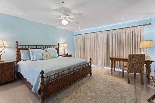 a bedroom with a bed and a desk and a ceiling fan at Beachfront - Royal Penthouse 3BR condo - BC352 in Palm-Eagle Beach
