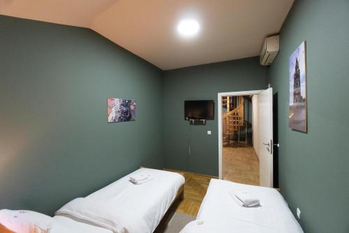 two beds in a room with a green wall at Aleksei Apartmani in Belgrade