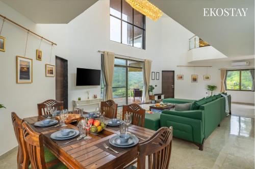 a living room with a table and a green couch at EKOSTAY - Infinity Villa with infinity pool in Āmbavna