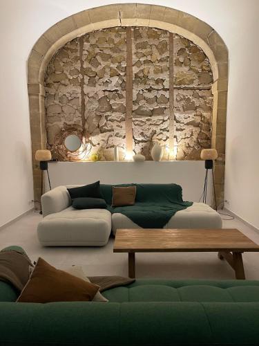 - un salon avec un canapé vert et un mur en pierre dans l'établissement Couvent d'Aubignan - Maison de caractère & piscine, à Aubignan