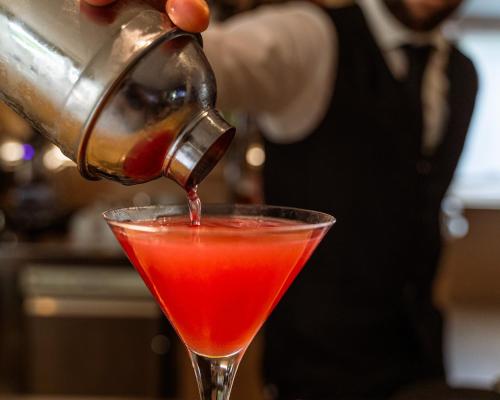 a person pouring a red drink into a martini glass at Hotel Stella Della Versilia in Marina di Massa