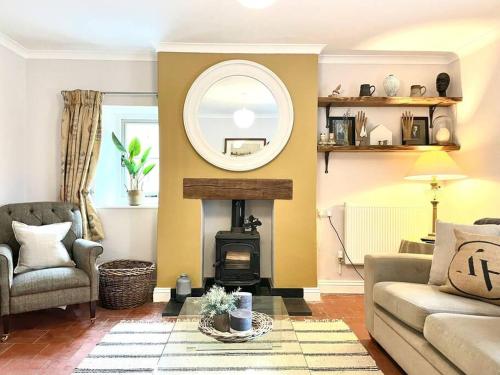 a living room with a fireplace and a mirror at New - Stylish Cotswold cottage in South Cerney