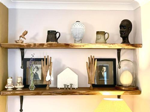 a shelf with pictures and other items on it at New - Stylish Cotswold cottage in South Cerney