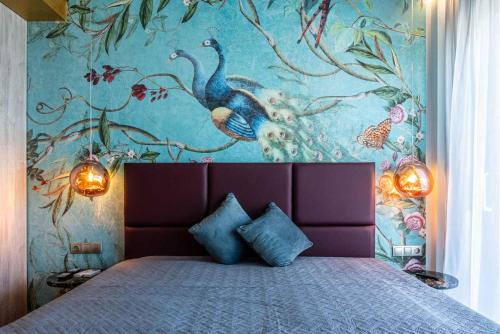 a bedroom with a large bed with a painting of peacocks at La Rêve Luxury Apartments in Hersonissos