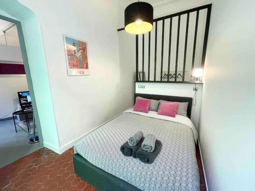 - une petite chambre avec un lit et des oreillers roses dans l'établissement Cosy appartement, moderne, fuchsia, industriel, à Nice
