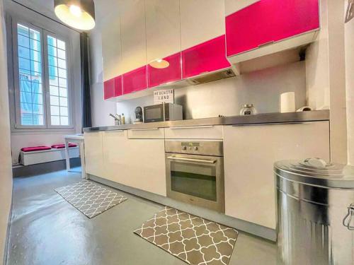 La cuisine est équipée de placards rouges et d'un four. dans l'établissement Cosy appartement, moderne, fuchsia, industriel, à Nice