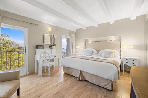 a bedroom with a bed and a desk and a balcony at La Chèvre d'Or in Èze