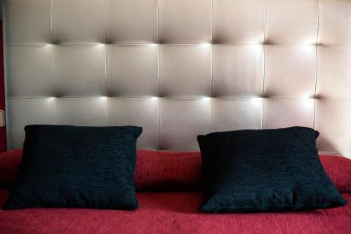 a red couch with two black pillows on it at Hotel Cim Valles in Santa Perpetua de Moguda