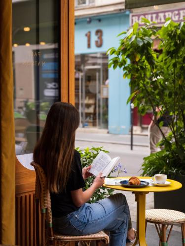 a woman sitting at a table reading a book at La Fantaisie in Paris
