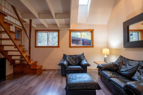 a living room with leather furniture and a staircase at Au Chic Chalet des Chutes Chic Chalet in Sainte-Melanie