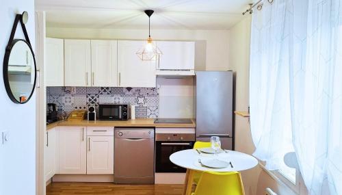 une petite cuisine avec une table blanche, une table et des chaises dans l'établissement Le Fatsia - Rennes Gare T2, à Rennes