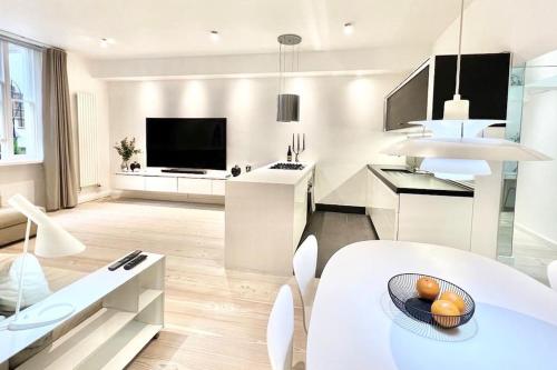 a white living room with a table and a tv at Stunning 4 bed flat near Notting Hill and Hyde park in London