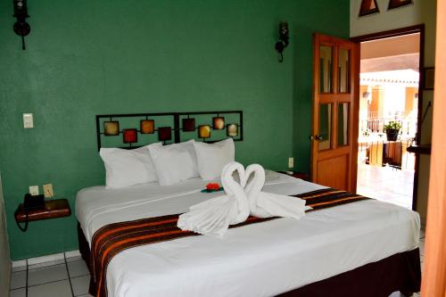 a bedroom with a bed with a white ribbon on it at Hotel Aldama in Colima