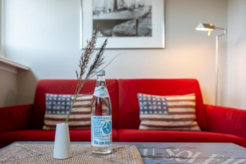 a bottle on a table in front of a red couch at Sylt Rooms 6 - Long Island Suite in Westerland (Sylt)