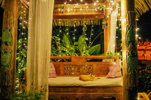 a cat sleeping on a bed in a gazebo with lights at West Indies Cottage in Pointe-Noire