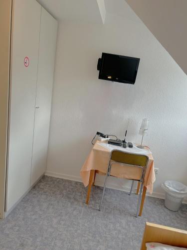 a room with a table and a tv on the wall at Hotel Haus Schwan Köln in Cologne