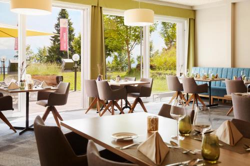 a restaurant with tables and chairs and large windows at Rigi Kaltbad Swiss Quality Hotel in Rigi Kaltbad
