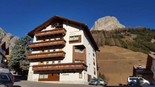 a building with wooden balconies and a mountain at Supermountainski Colfosco in Colfosco